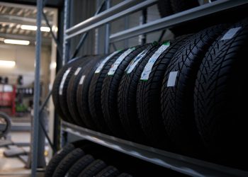 Brand new big variety of car's tyres on shelf with prices at store or warehouse.