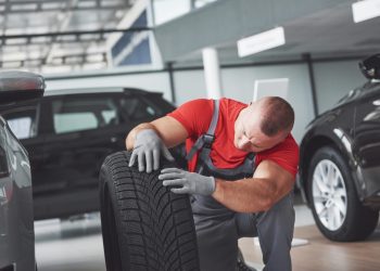 Mechanic holding a tire tire at the repair garage. replacement of winter and summer tires.